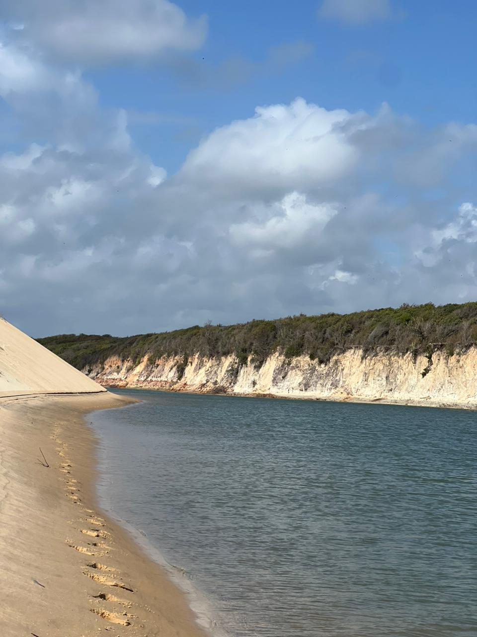 Rio cercado por dunas e vegetação em Barra Nova.